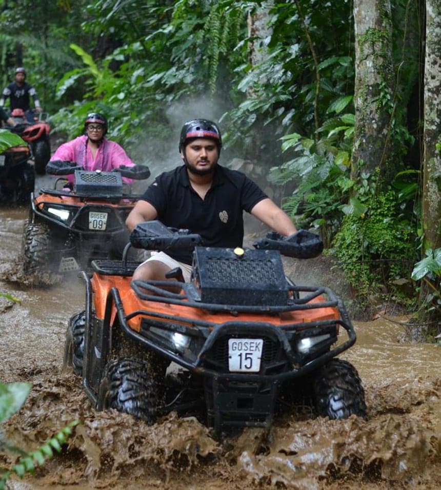 A Gosek Adventure rider powering a quad bike through a muddy jungle track, riders following behind, in Gianyar