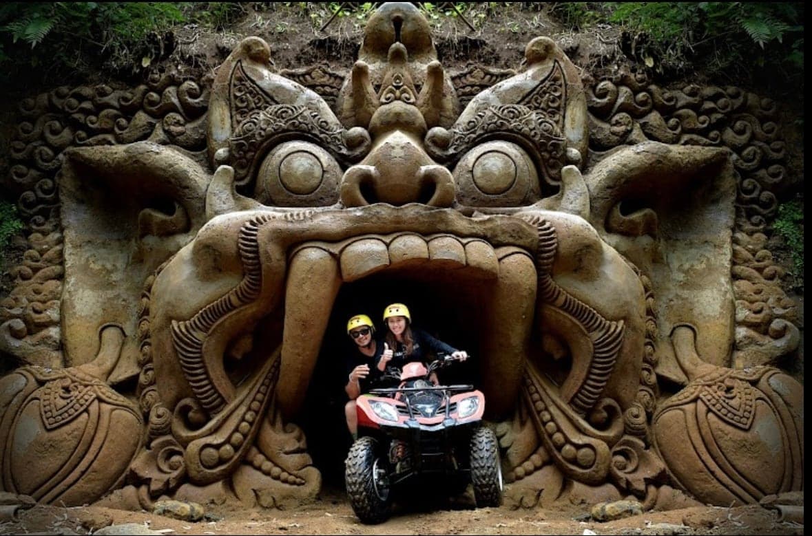 A tandem quad bike emerging from a hand-carved stone cave mouth on the Gosek Temple Run track in Gianyar, Bali